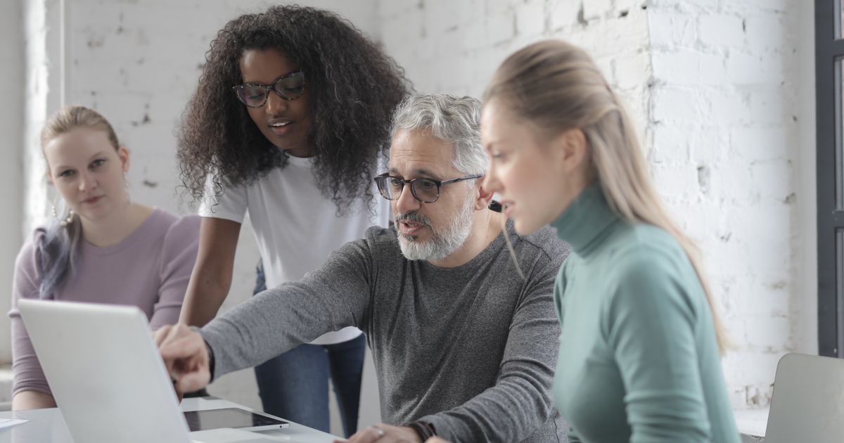 A team collaborating around a laptop