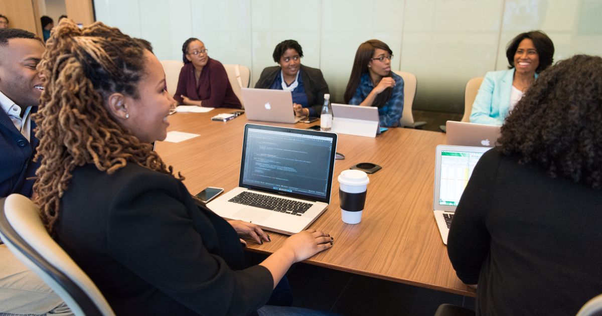 A diverse professional team collaborating with laptops around a boardroom table