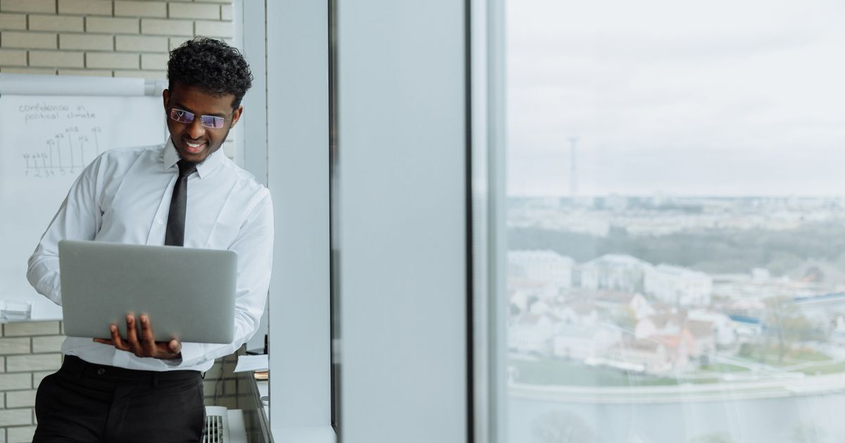 A businessman working on a laptop by an office window