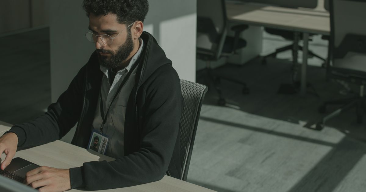 An employee with an ID badge working at a laptop
