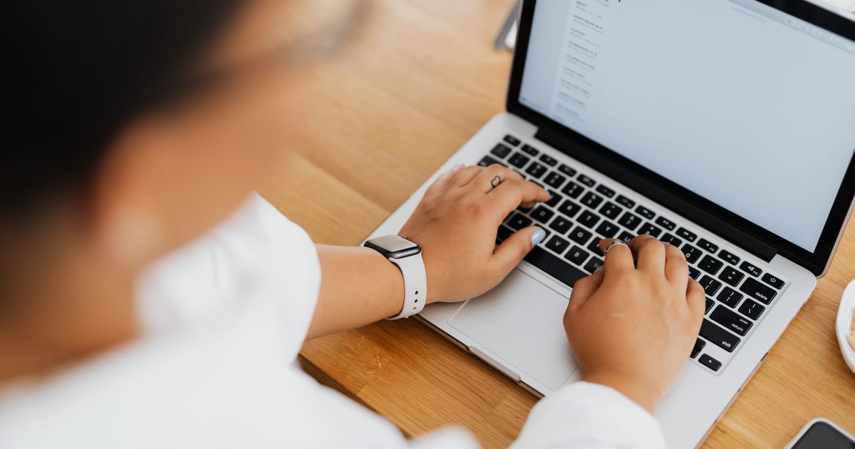 Close-up of a person typing an email on a laptop