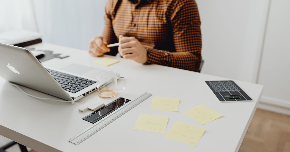A person working at a tidy desk with a laptop and notes