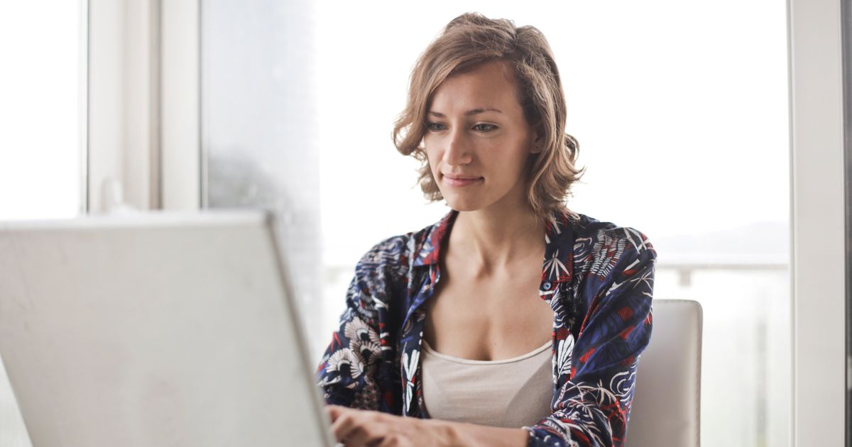 A focused professional working at a laptop by a bright window