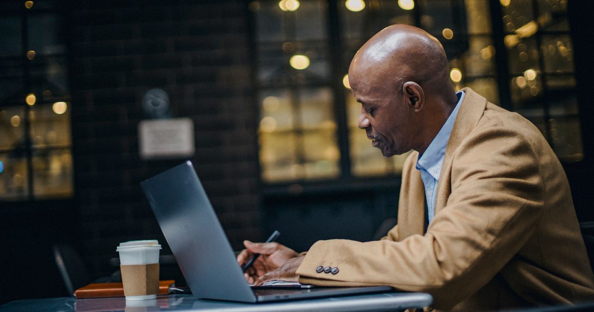 A professional writing on a laptop in the evening
